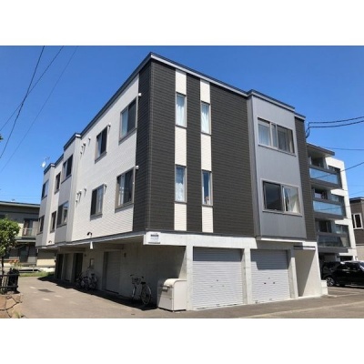 建物外観。1階に車庫を備えた3階建てのアパートです。