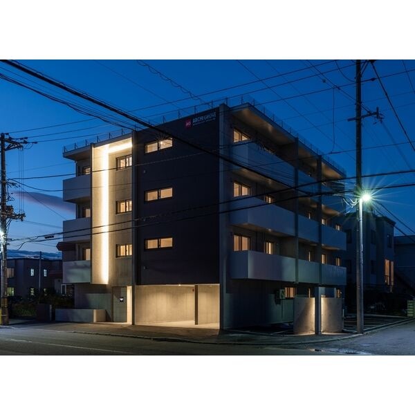 夜の建物外観。照明が灯るエントランスと外壁