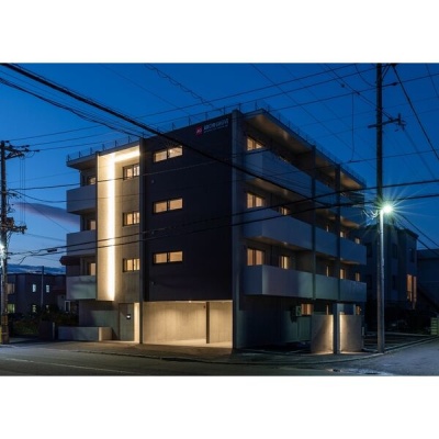 夜の建物外観。照明が灯るエントランスと外壁