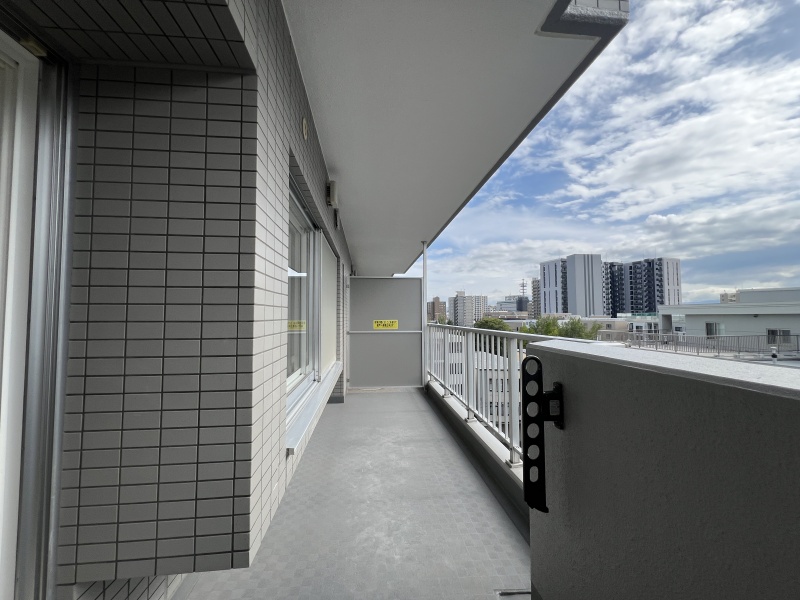青空と都市の眺望を愉しめるゆとりのバルコニー空間。心地よい時間と実用的な物干し環境を両立します。