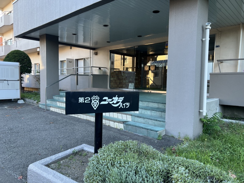 手入れされた緑とシックな銘板が調和する、品格と温もりに満ちたエントランスアプローチ。