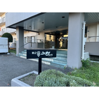 手入れされた緑とシックな銘板が調和する、品格と温もりに満ちたエントランスアプローチ。
