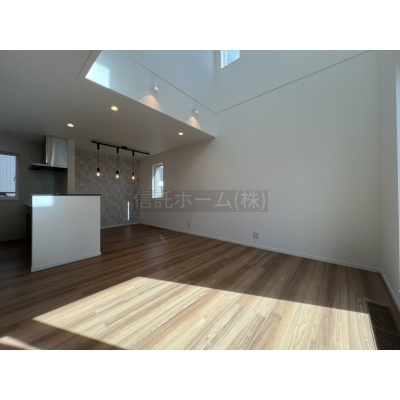 高窓から自然光が差し込む、吹抜けのあるリビング。天井の高さが心地よい空間を演出します。