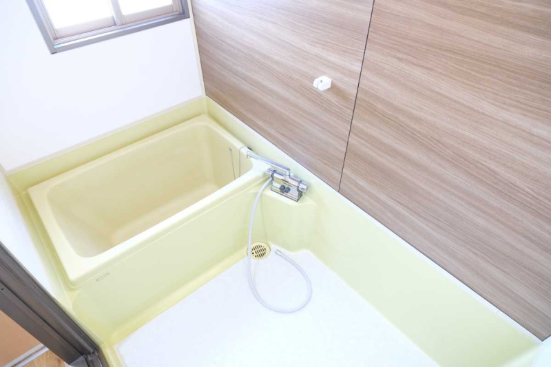 木目調の壁パネルが落ち着いた印象の浴室。窓があり、換気しやすい空間です。