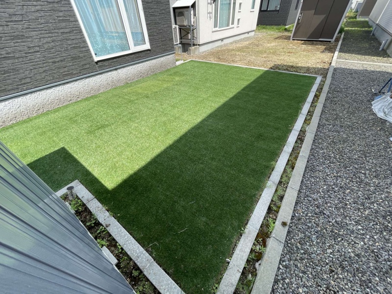 千歳市北陽の都市ガスエコジョーズ全室床暖房の平家戸建です。リビングの掃き出し窓から、人工芝の南庭に出ることが可能です。